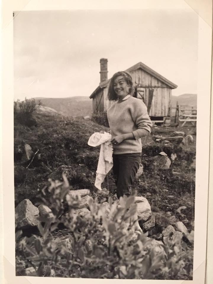 A woman crossing the rocks beside the cabin at Heimdalen
