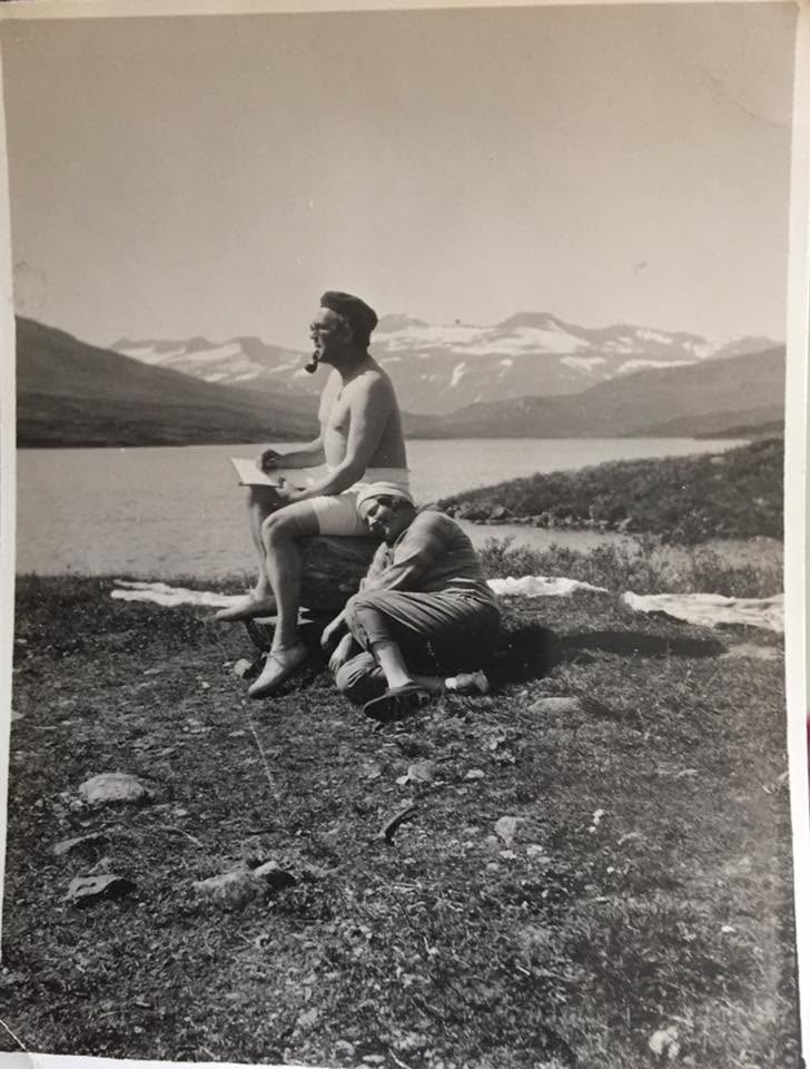 A man sitting on a rock above the lake at Heimdalen, snow still on the mountains beyond